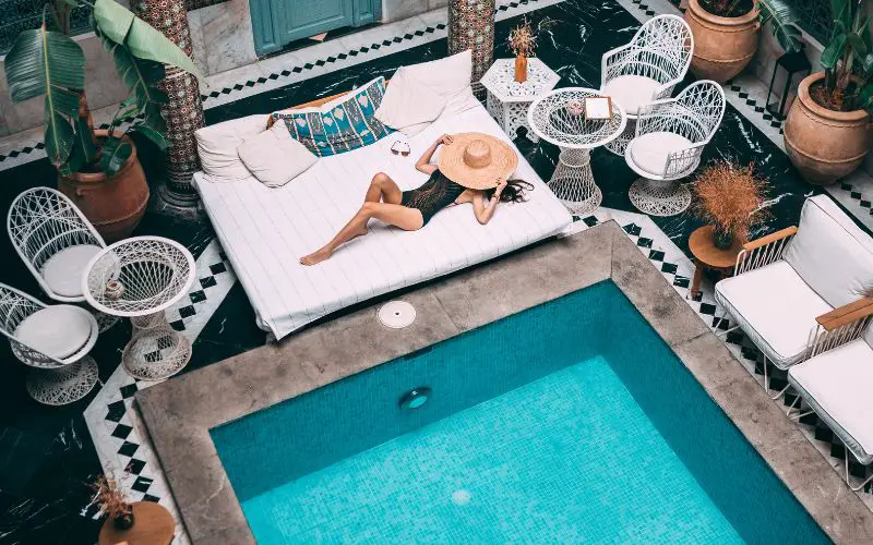 Une femme allongée au bord de la piscine d'un riad à Marrakech